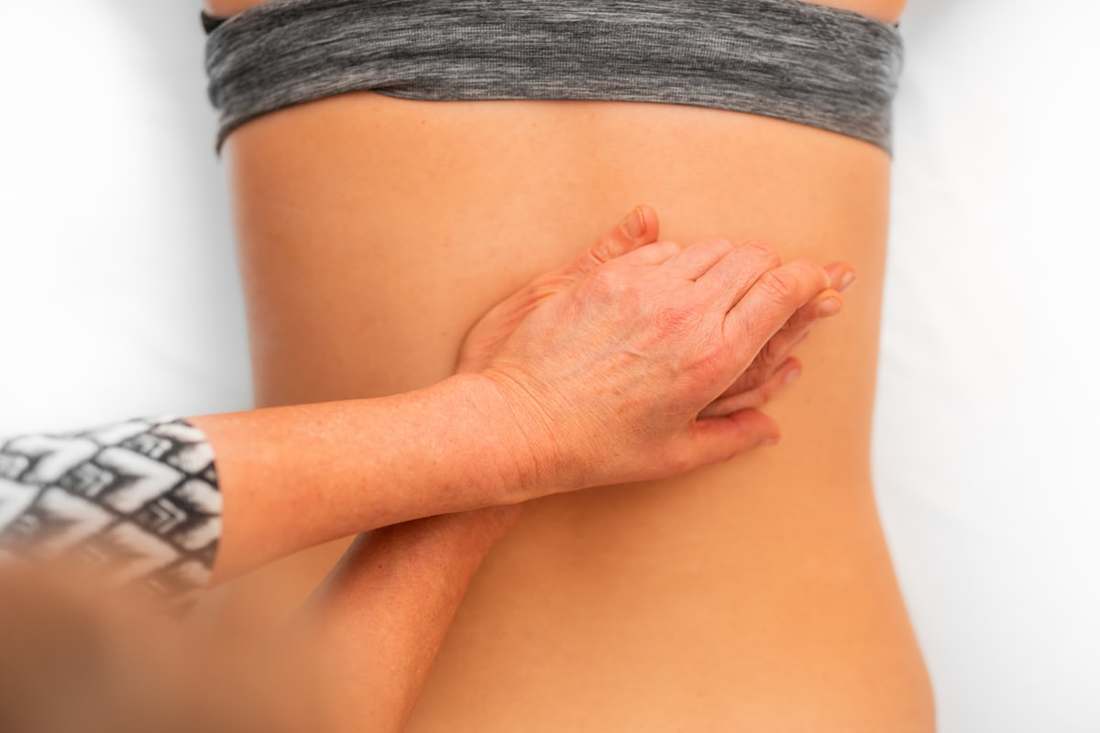 Physiotherapist's hands assessing a patient's lower back