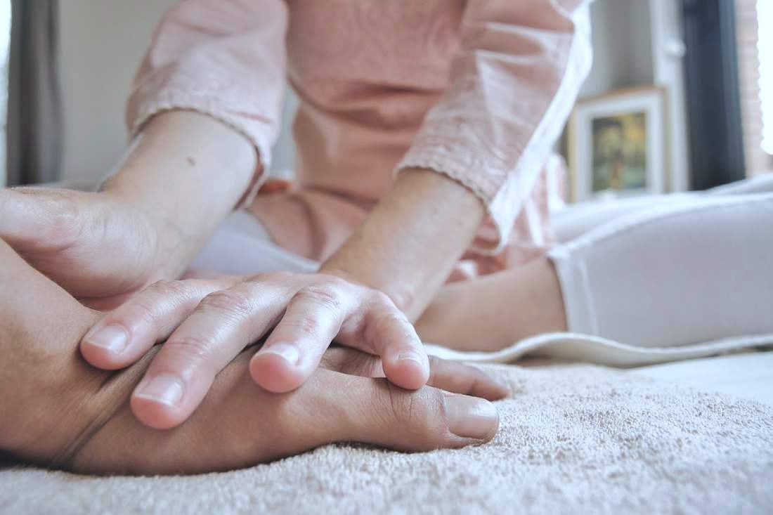Physiotherapist's hands offering reassurance to a patient